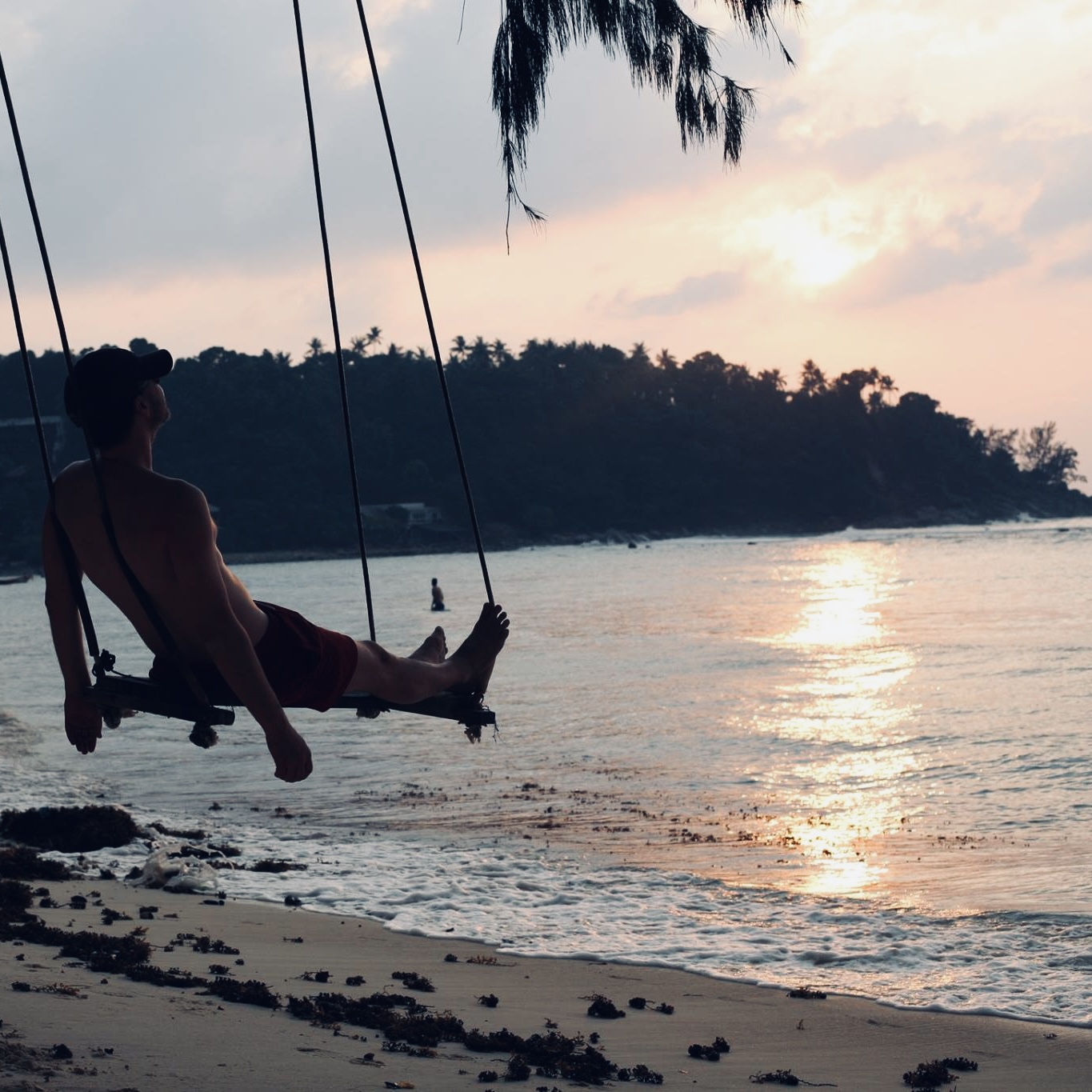Espen Kjendlie on a beach swing at sunset looking out over the sea